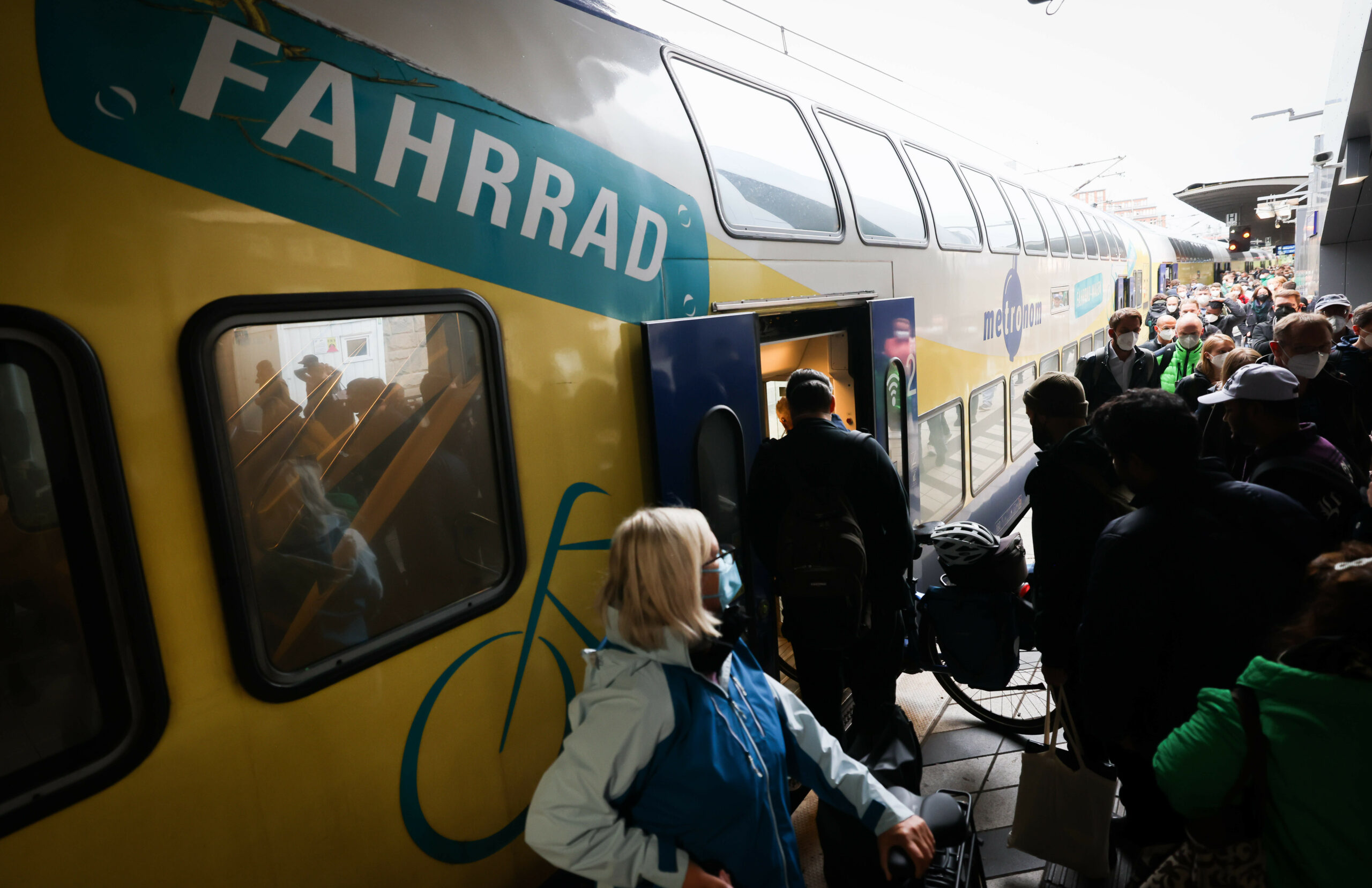 Zahlreiche Reisende, teilweise mit Fahrrad, sind am Bahnsteig neben einem Metronom-Regionalzug im Hauptbahnhof zu sehen.