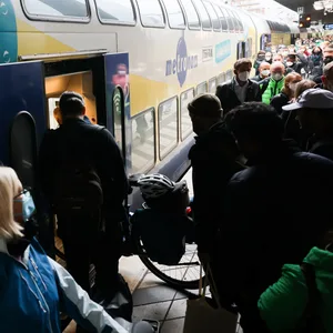 Zahlreiche Reisende, teilweise mit Fahrrad, sind am Bahnsteig neben einem Metronom-Regionalzug im Hauptbahnhof zu sehen.