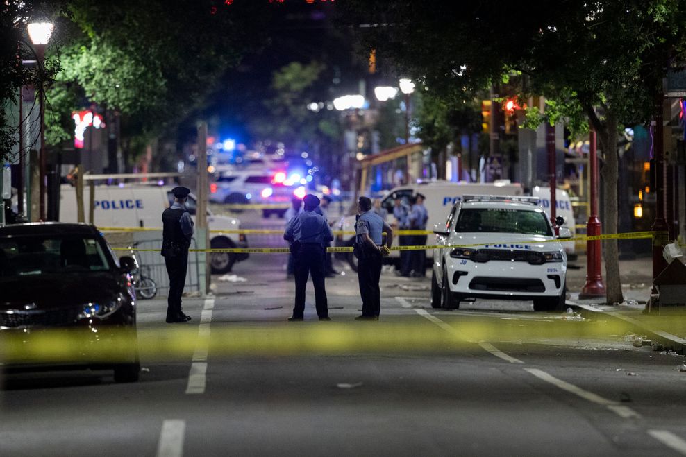 Polizisten und Ermittler der Polizei von Philadelphia stehen am Tatort auf der Straße.