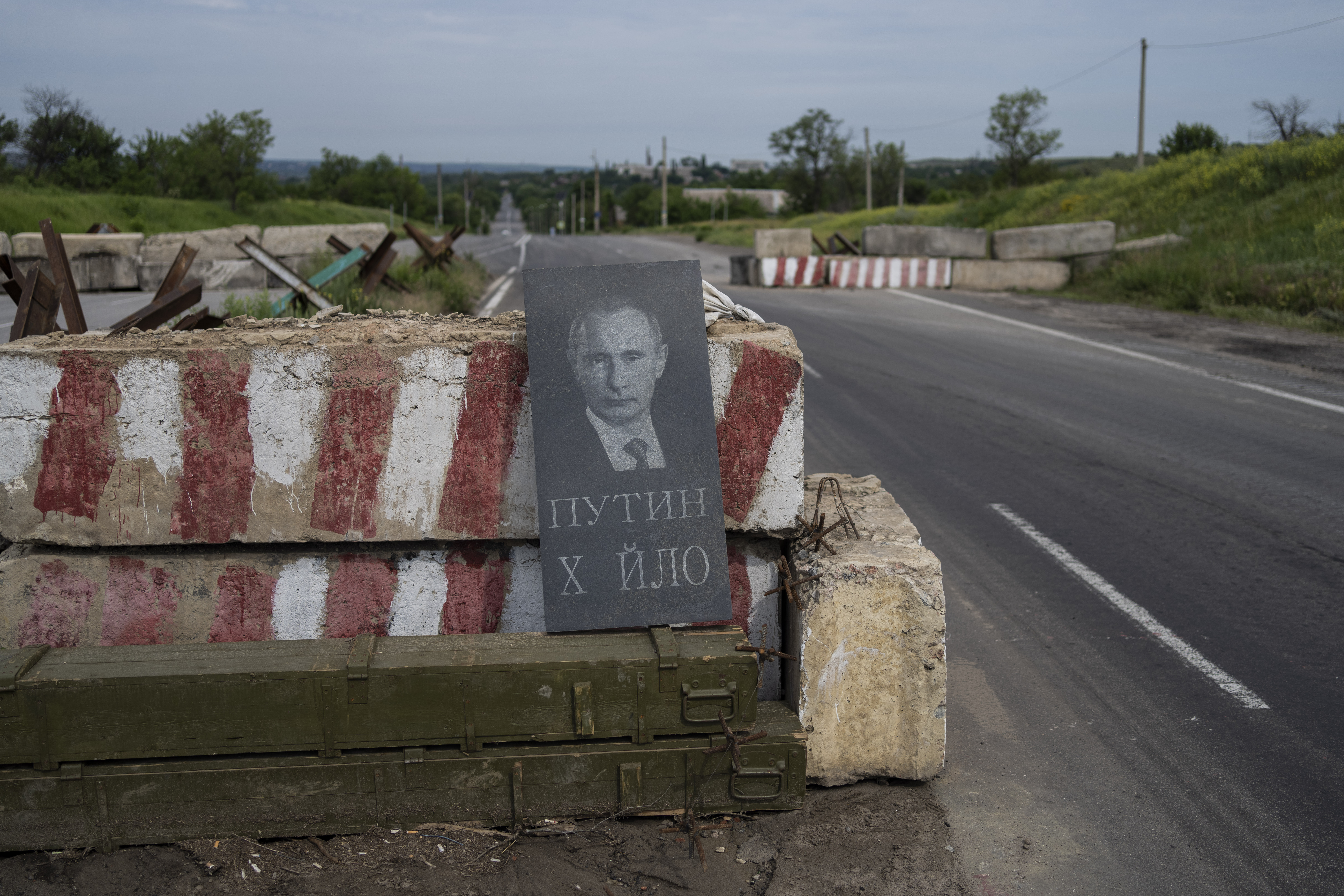 Ein Grabstein mit dem Konterfei des russischen Präsidenten Putin und der Aufschrift „Schwachkopf Putin“ steht angelehnt an einer Straßensperre nahe der Frontlinie im Donbass.