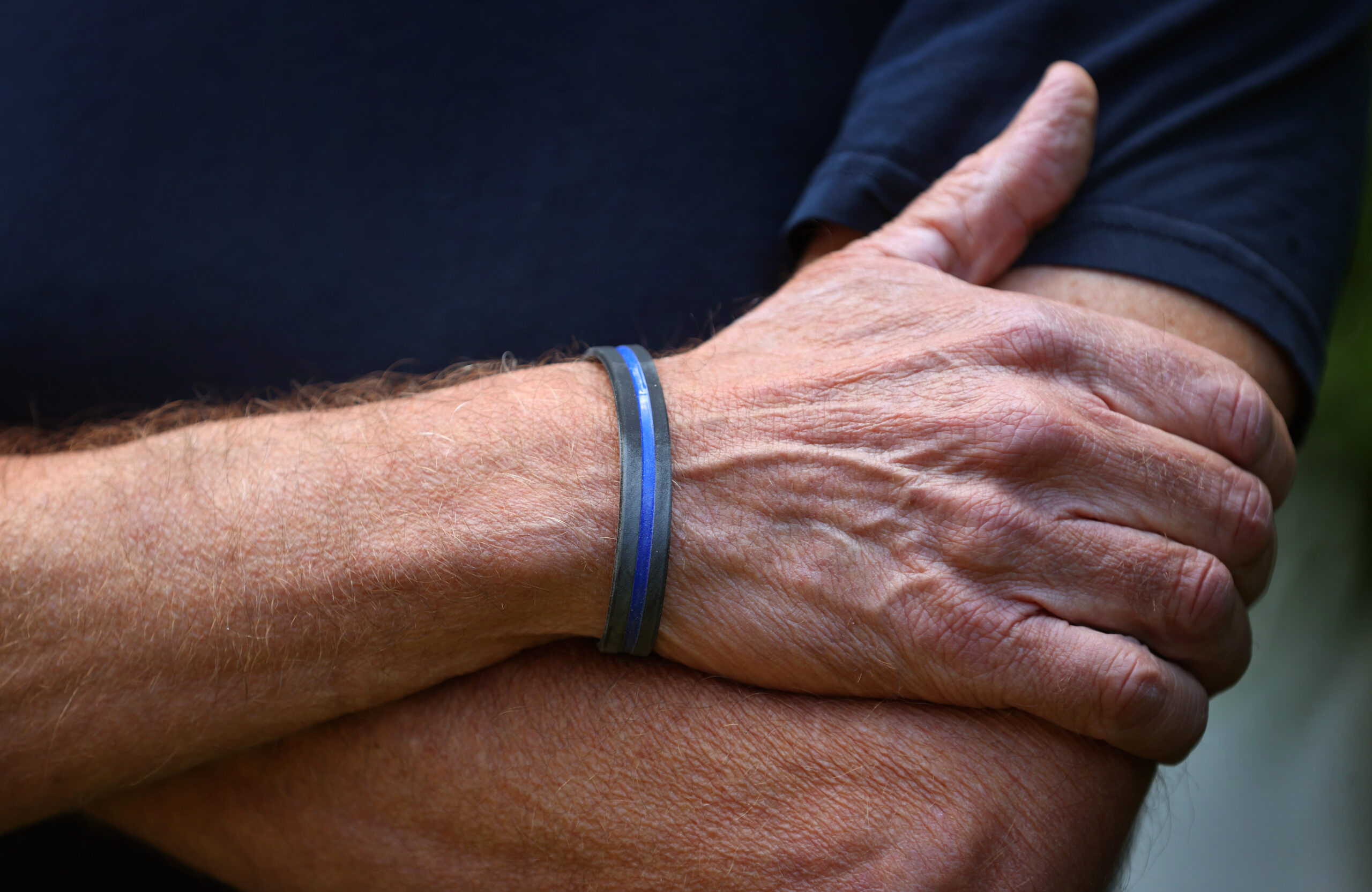 Ein Mann trägt an seinem Handgelenk ein "Thin Blue Line" Armband aus Silikon.