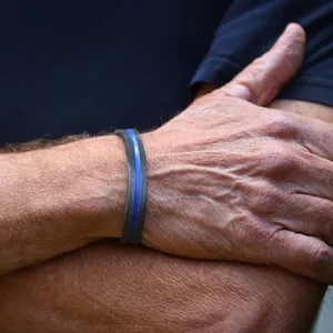 Ein Mann trägt an seinem Handgelenk ein "Thin Blue Line" Armband aus Silikon.