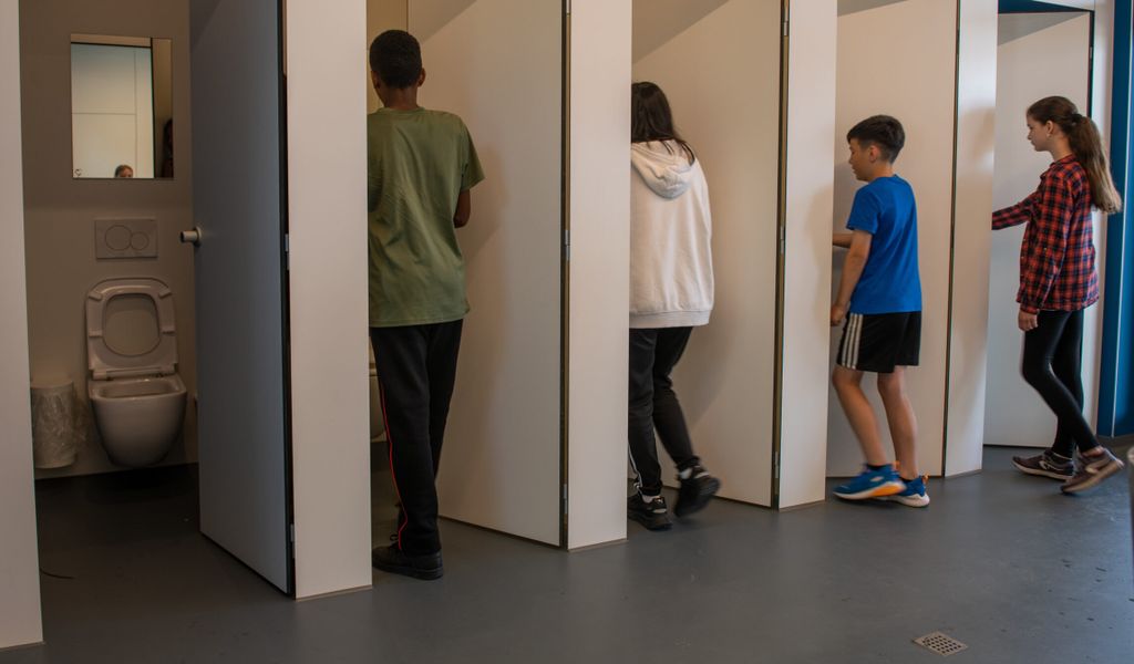 Jungen und Mädchen gehen in eine Unisextoilette an der Sägefeldschule.