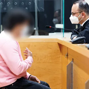 Ein Mann im rosa Hemd spricht mit einem Anwalt in Robe.