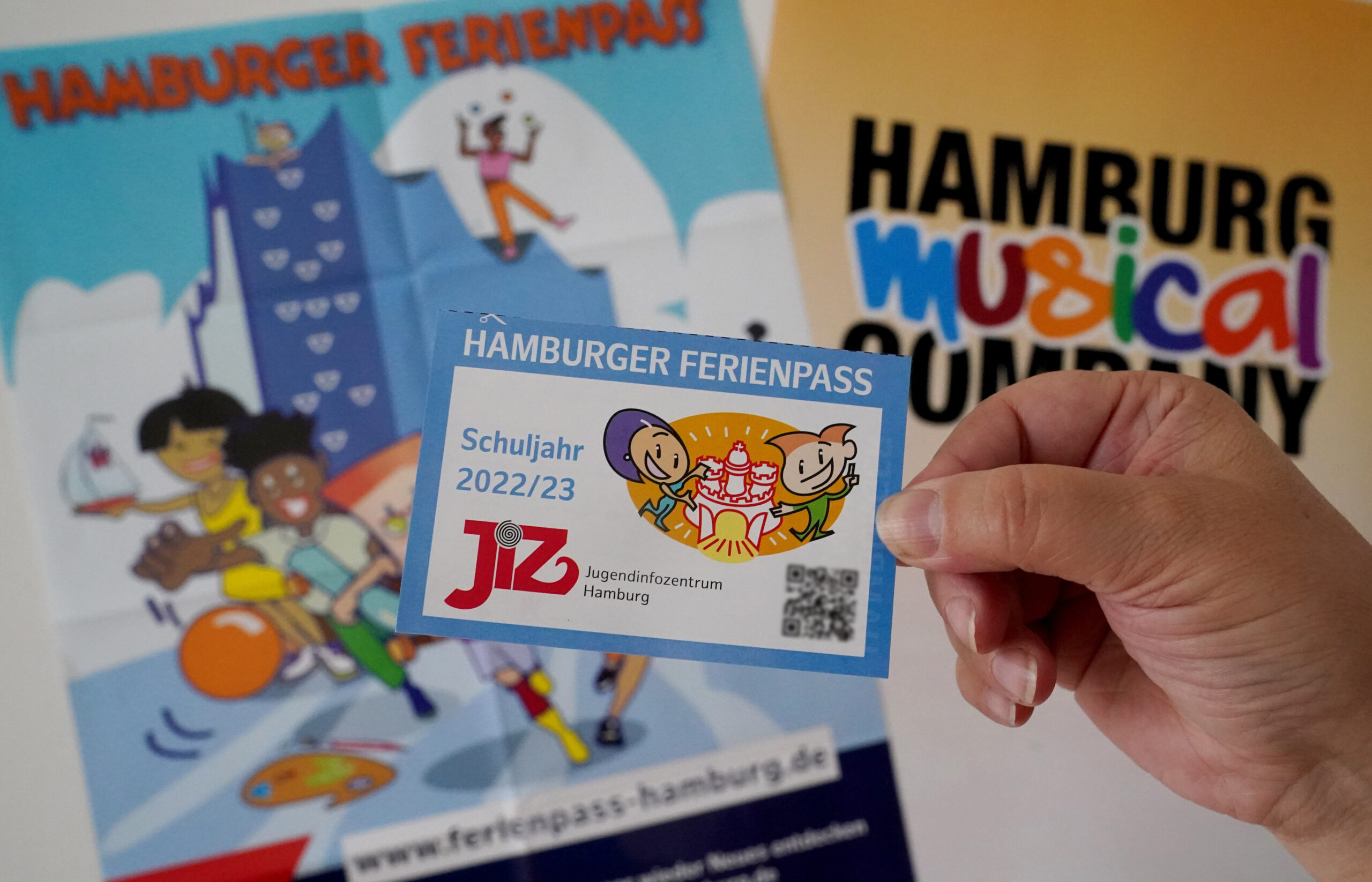 Eine Frau hält den neuen Ferienpass der Stadt Hamburg in der Hamburg Musical Company hoch.