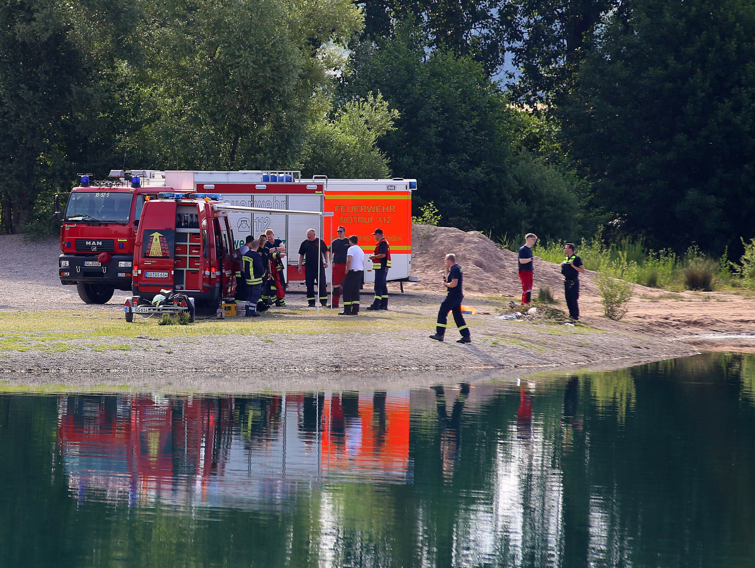 Fahrzeuge der Feuerwehr stehen an einem Baggersee bei Göttingen.