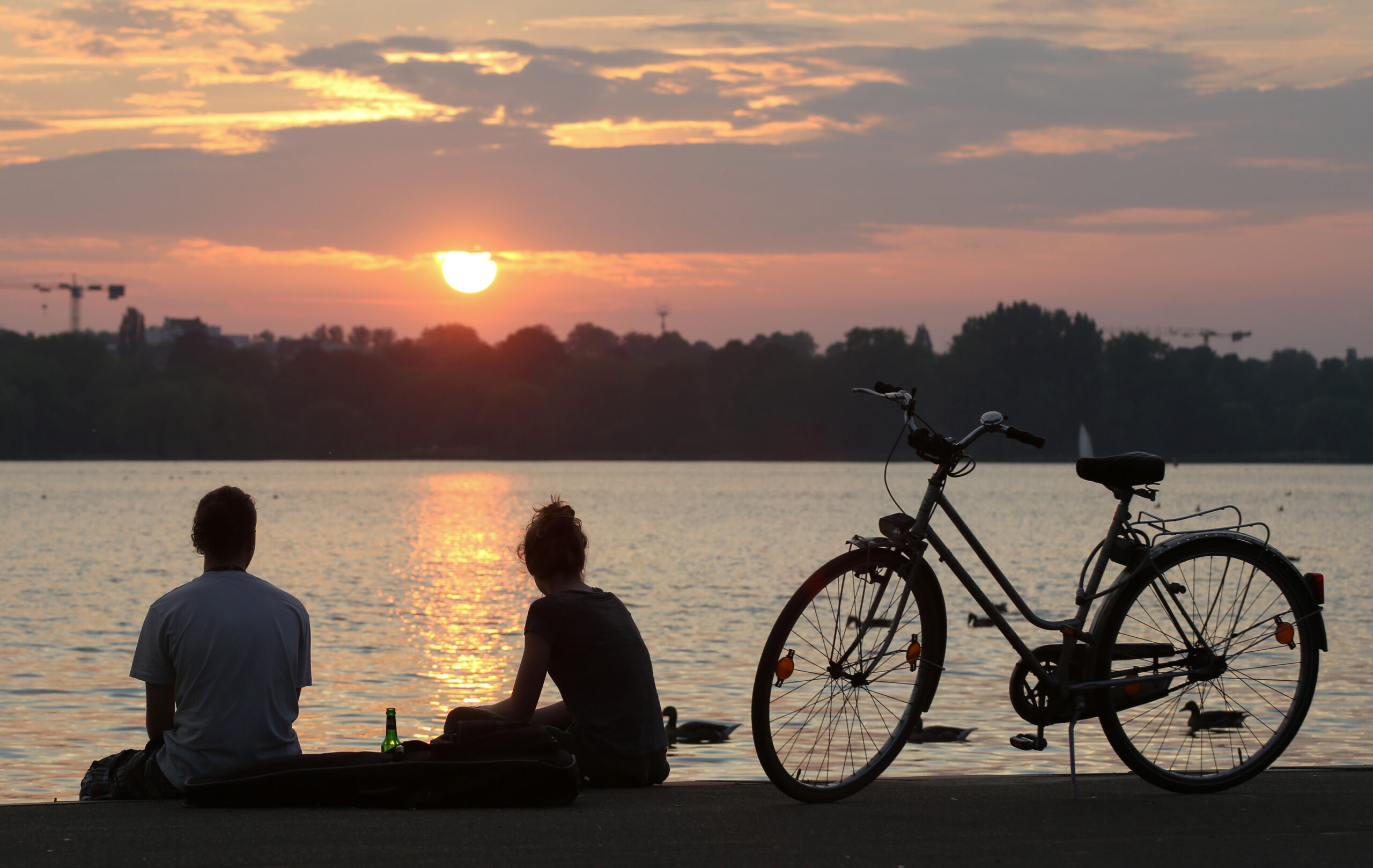 Menschen setzten an der Außenalster und blicken auf den Sonnenuntergang