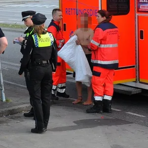 Ein Mann mit nacktem Oberkörper steht neben einem Rettungswagen