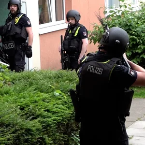 Mit Maschienpistolen im Anschlag nähern sich Polizisten dem Haus.