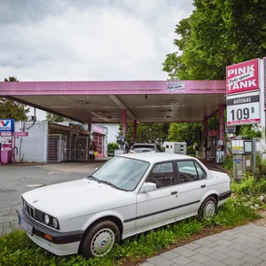 Pinkfarbene Tankstelle mit altem Auto davor
