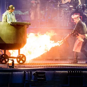 Lindemann mit einem Flammenwerfer neben einem großen Kochtopf, in dem ein Mann steht