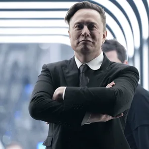 Elon Musk verschränkt die Arme vor der Brust.