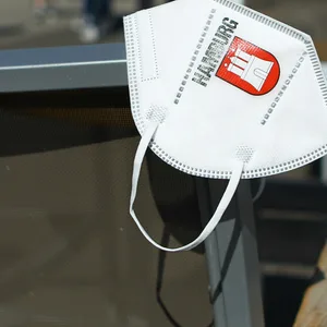Eine Maske mit dem Logo von Hamburg hängt an einem Stuhl eines Cafés in der Hamburger Innenstadt.