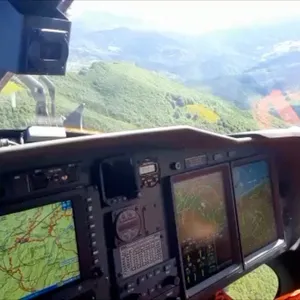 Ein italienischer Feuerwehrhubschrauber sucht die Absturzstelle eines Hubschraubers ab.