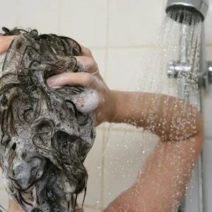 Eine Frau unter der Dusche wäscht sich ihre Haare