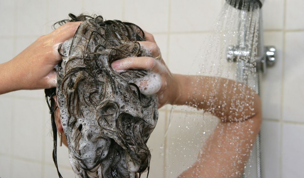 Eine Frau unter der Dusche wäscht sich ihre Haare