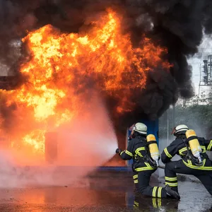 Zwei Feuerwehrmänner bekämpfen einen Brand.