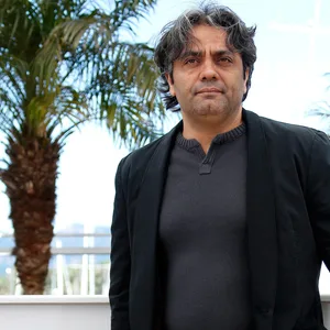 Rassulof steht bei einem Photocall für das Filmfestival in Cannes, hinter ihm Palmen