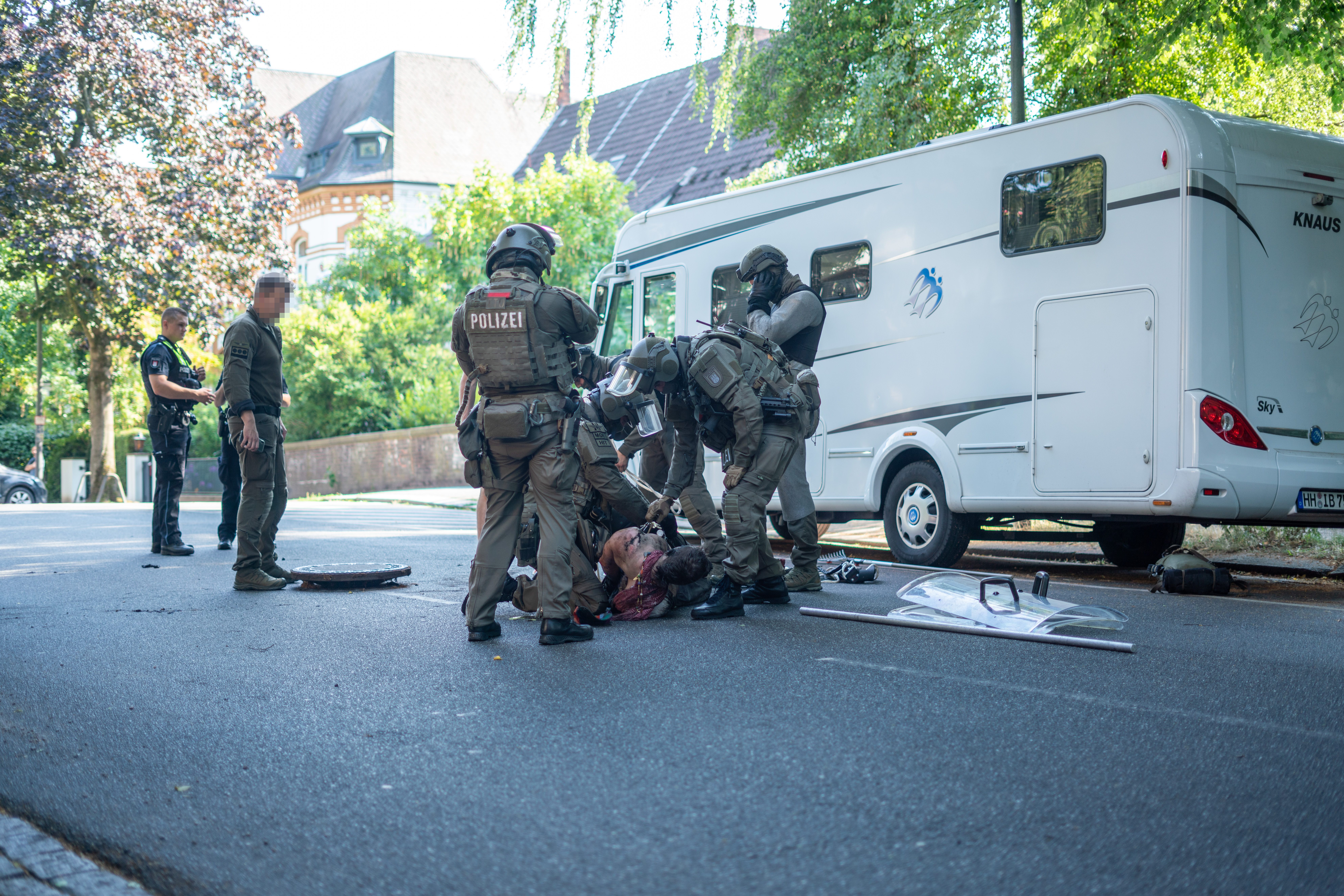 Bewaffnete SEK-Beamte ziehen einen Mann aus der Kanalisation, ein Gully-Deckel liegt auf der Straße