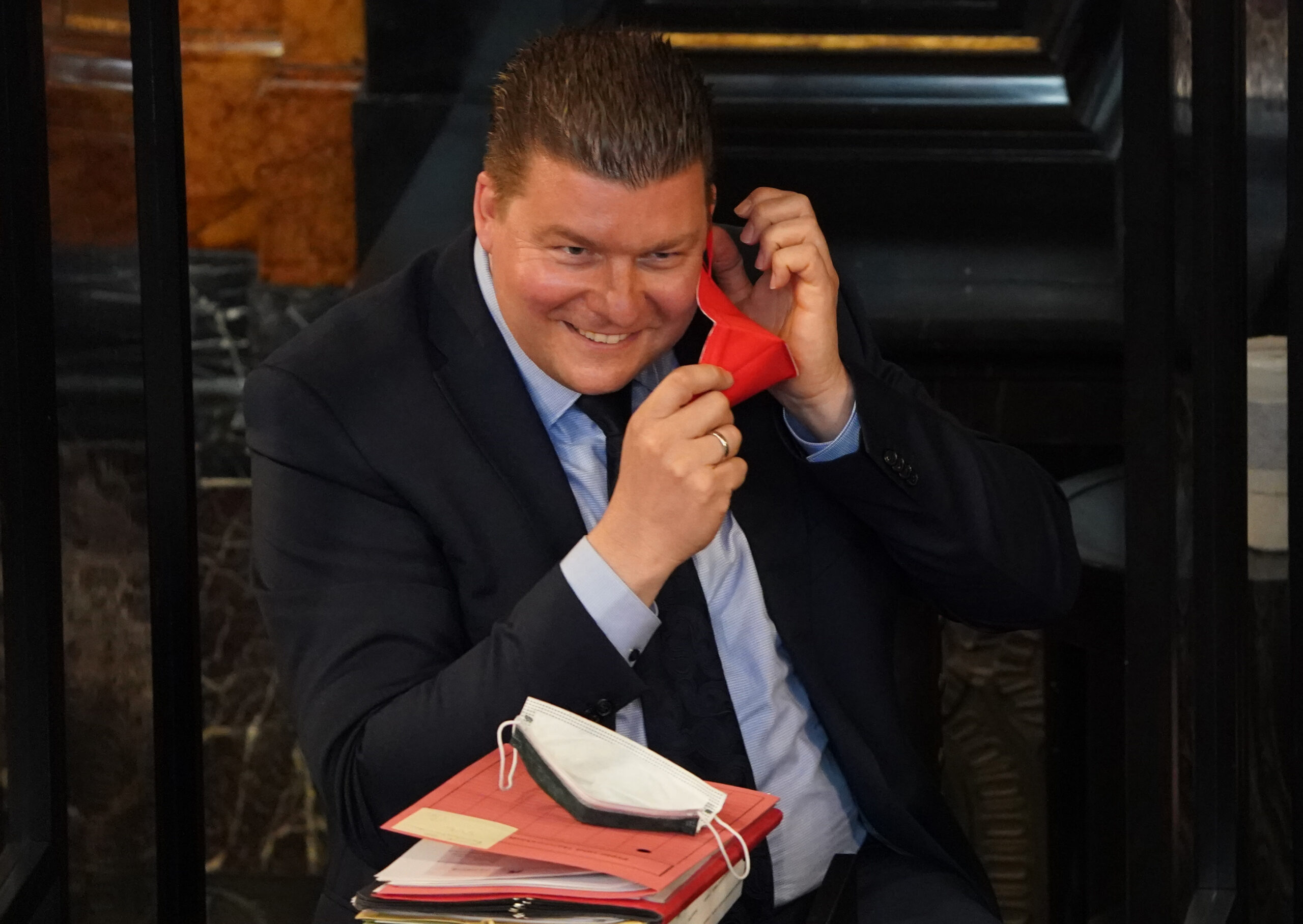 Andreas Dressel (SPD) setzt sich eine rote FFP2-Maske auf.