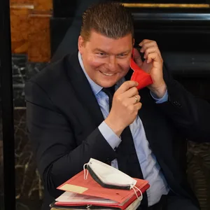 Andreas Dressel (SPD) setzt sich eine rote FFP2-Maske auf.