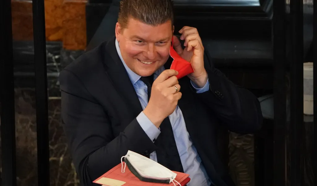 Andreas Dressel (SPD) setzt sich eine rote FFP2-Maske auf.