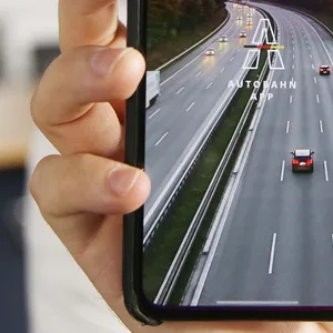 Ein Mann hält ein Handy mit der Autobahn-App in die Luft.