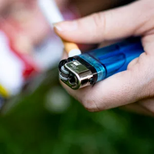 Eine Frau hält ein Feuerzeug und eine Zigarette in der Hand.