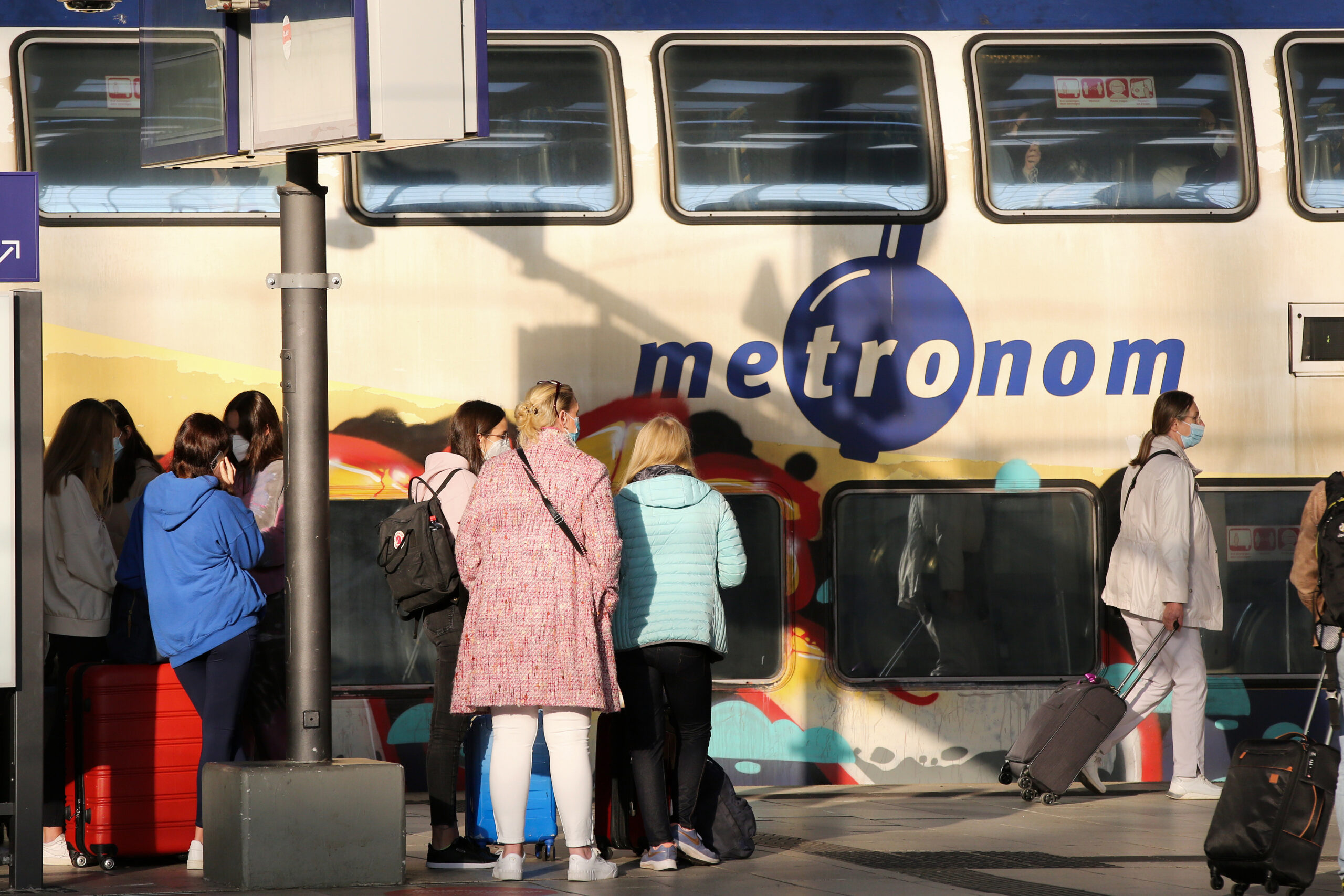 Reisende stehen im Hauptbahnhof vor einem Metronom.