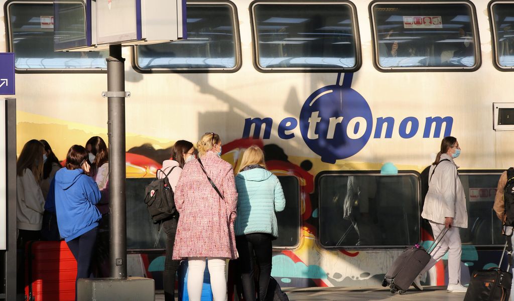 Reisende stehen im Hauptbahnhof vor einem Metronom.