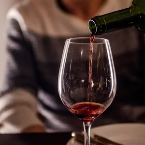 Eine Frau gießt zuhause Wein in ein Glas.