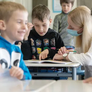 Eine Lehrerin betreut Grundschulkinder.