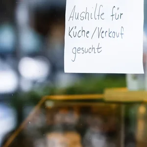 Ein Zettel mit der Aufschrift „Aushilfe für Küche/Verkauf gesucht“ hängt an der Scheibe einer Konditorei. (Symbolbild)