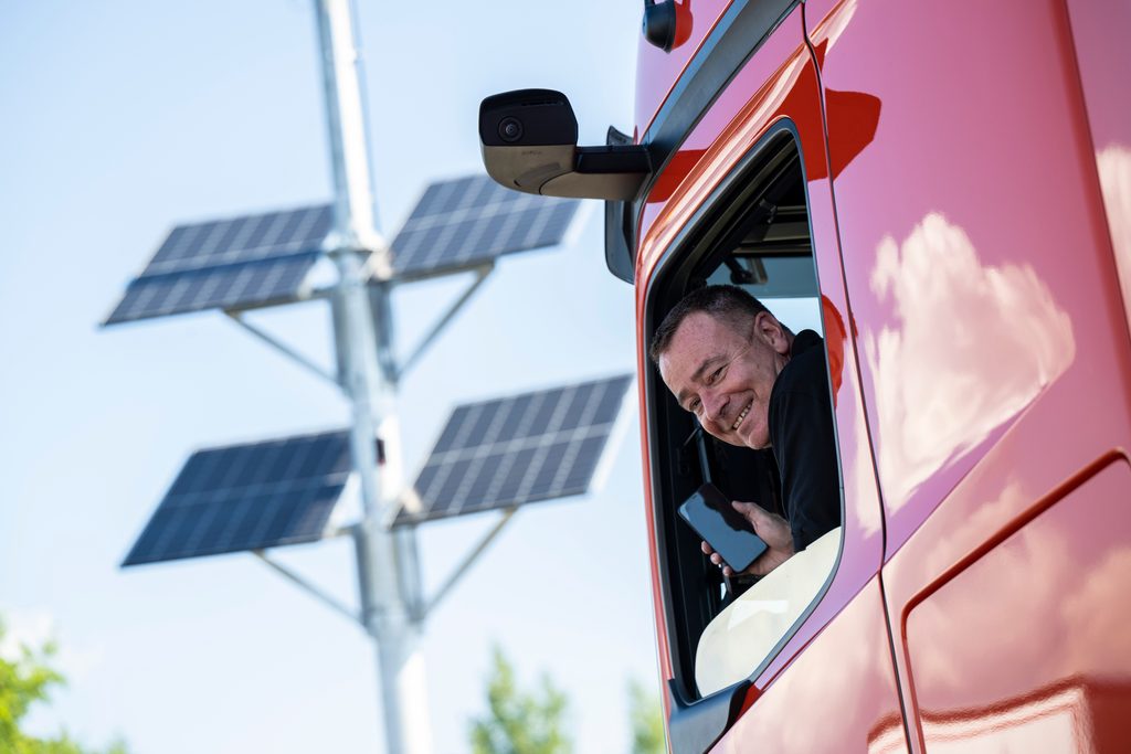 Ein Lkw-Fahrer mit einem Handy in der Hand.