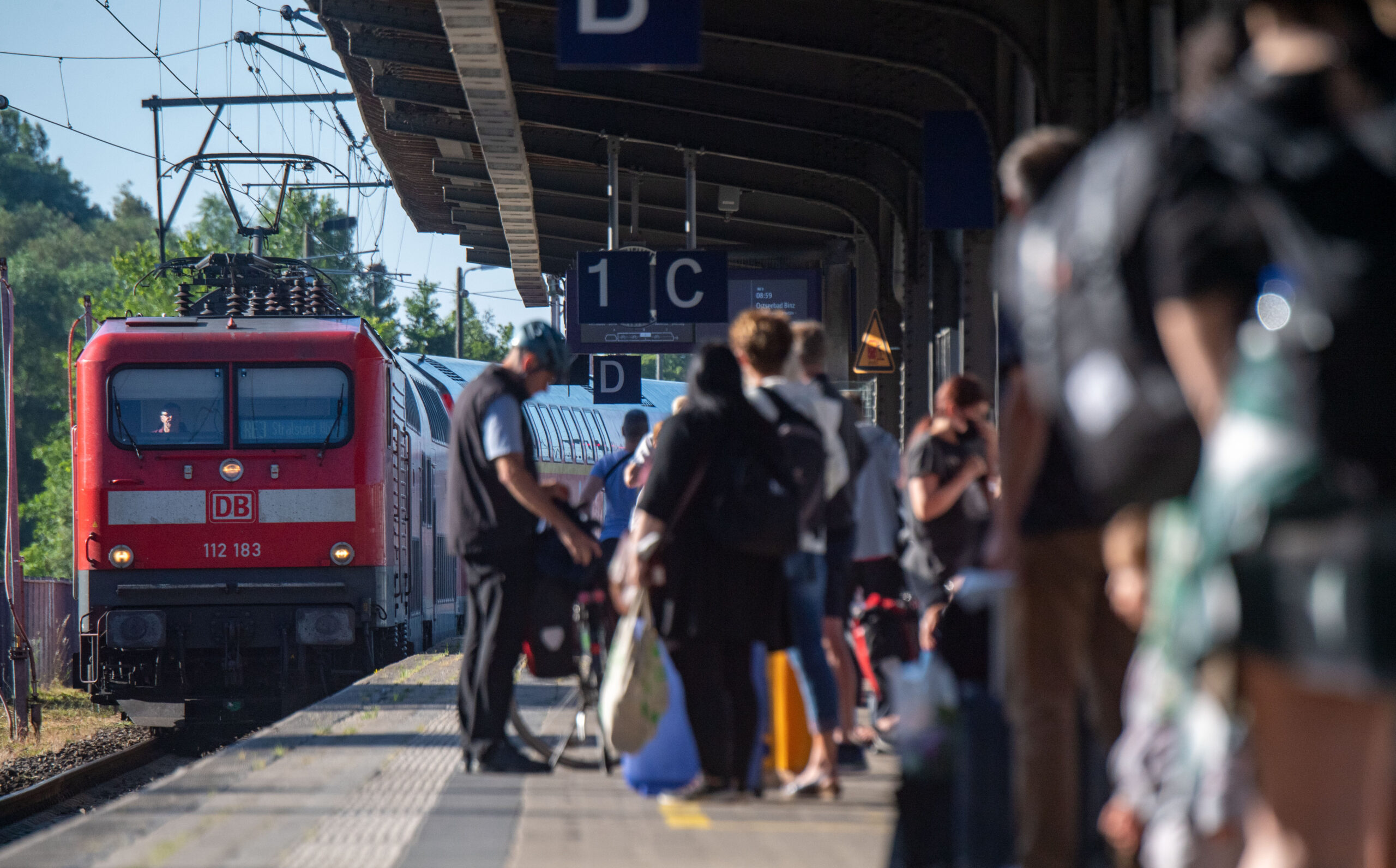 Fahrgäste warten im Bahnhof auf eine Regionalbahn. Wegen der Sommerferien waren Staus auf den Autobahnen erwartet worden, doch dort blieb es im Gegensatz zu den Zügen ruhig. (Archivbild)