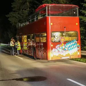 Rettungskräfte stehen neben einem Doppeldeckerbus.