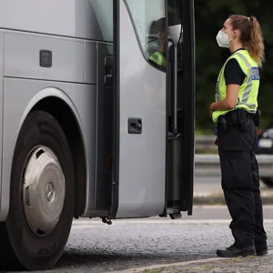 Eine Polizeibeamtin kontrolliert einen Reisebus. (Symbolbild)
