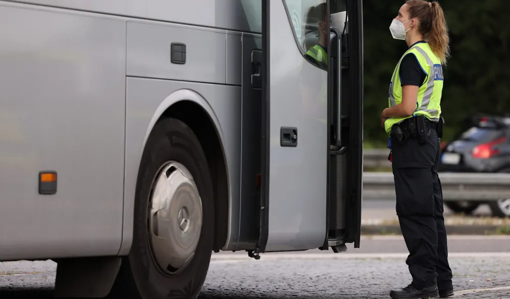 Eine Polizeibeamtin kontrolliert einen Reisebus. (Symbolbild)