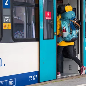 Eine Frau mit Rucksack steigt in einen Zug.