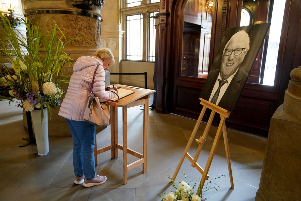 Eine Frau trägt sich im Rathaus in das Kondolenzbuch für Uwe Seeler ein.