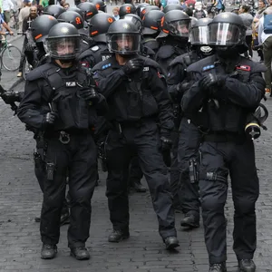 Polizisten mit Helmen gehen während des G20-Gipfels im Schanzenviertel zwischen Passanten und Radfahrern durch eine Straße. (Archivbild)