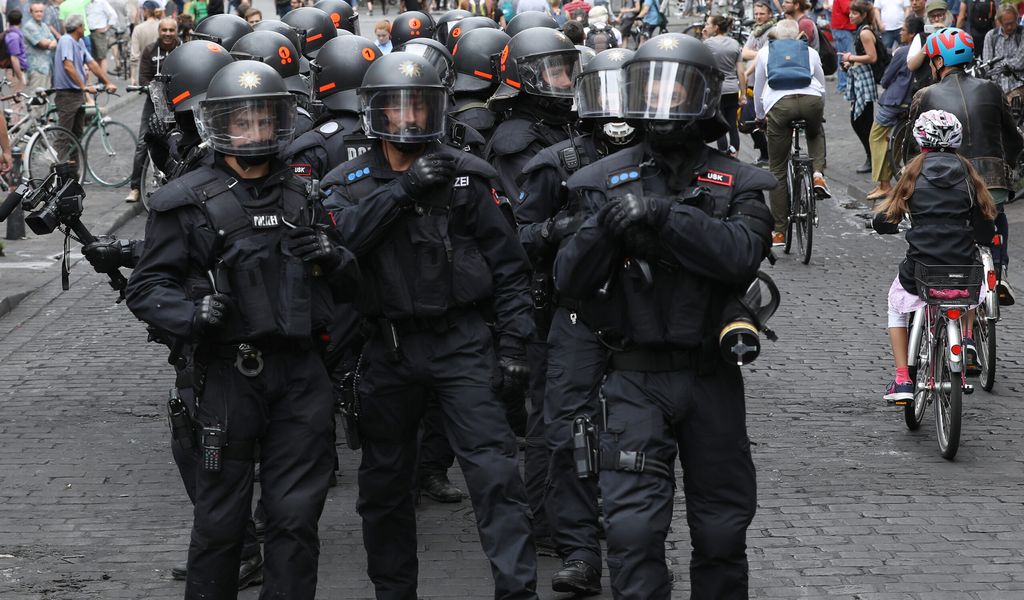 Polizisten mit Helmen gehen während des G20-Gipfels im Schanzenviertel zwischen Passanten und Radfahrern durch eine Straße. (Archivbild)