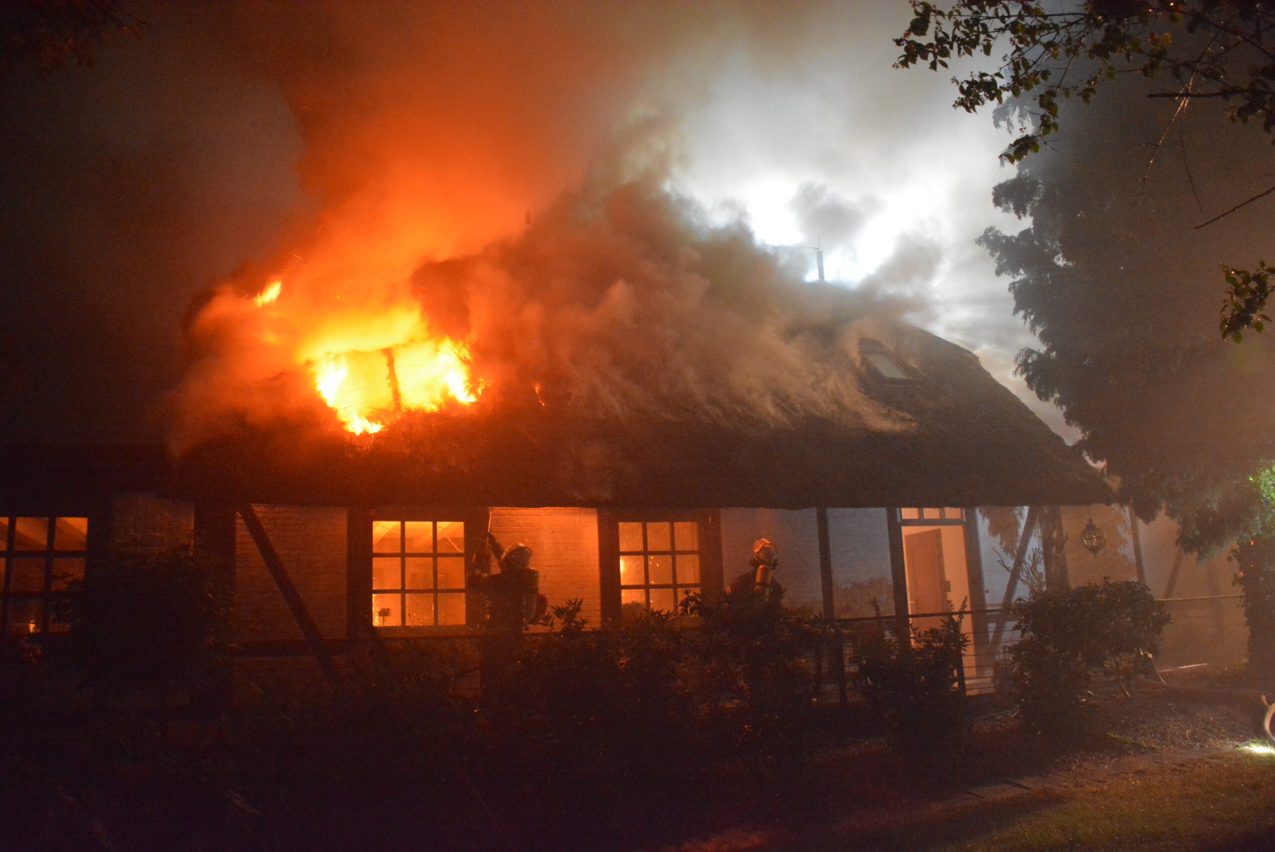 Feuerwehrkräfte löschen die Flammen, die sich durch das Dach fressen.