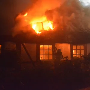 Feuerwehrkräfte löschen die Flammen, die sich durch das Dach fressen.