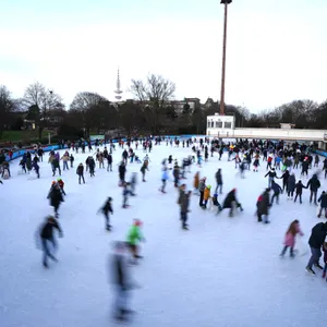 Viele Menschen fahren auf der Eisbahn im Park „Planten un Blomen“ Schlittschuh