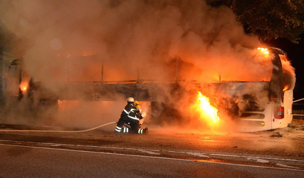 Feuerwehrleute löschen einen brennenden Reisebus in Hamburg-Horn.