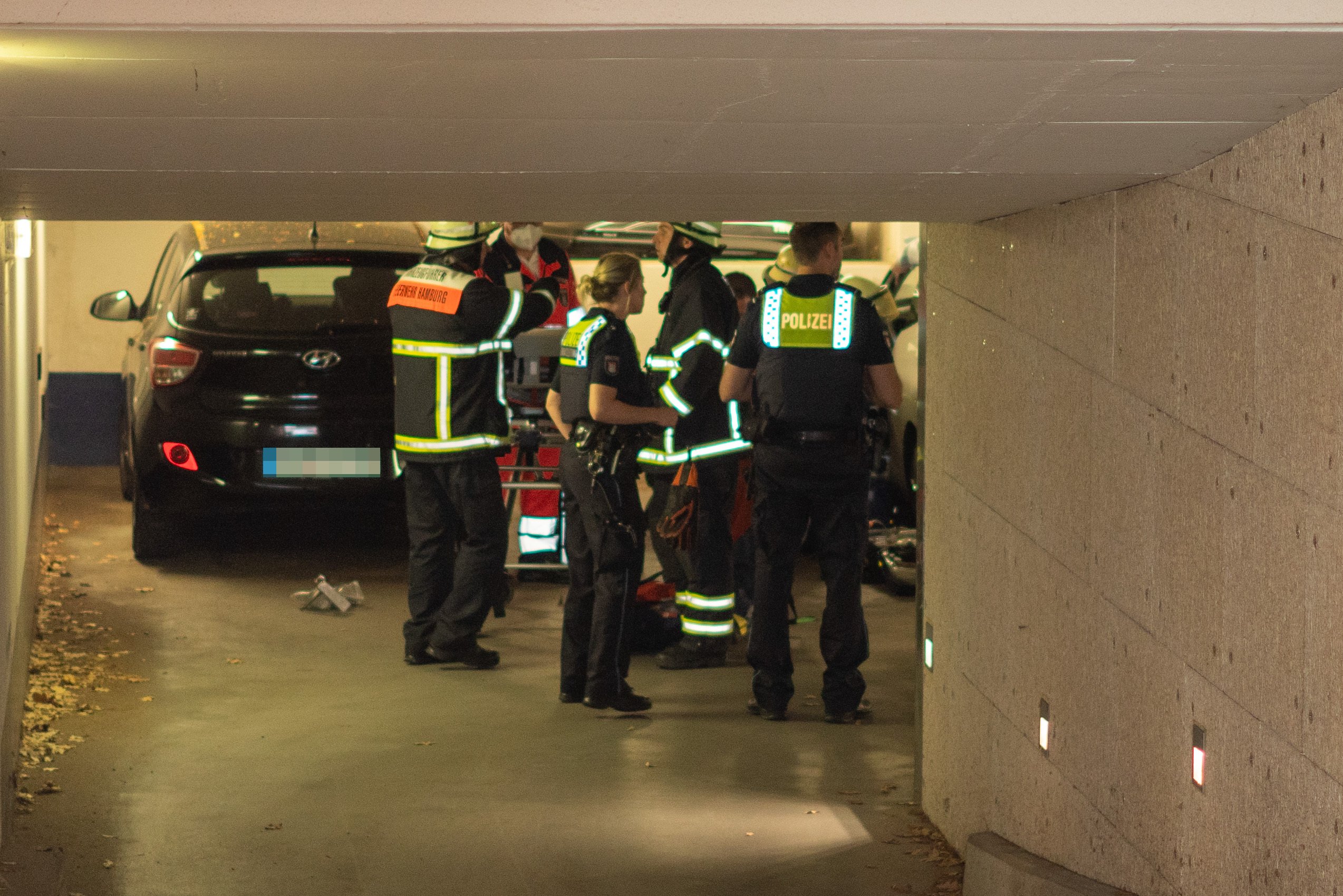Rettungskräfte stehen in einer Tiefgarage neben Autos