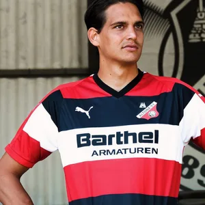 Ein Mann steht im schwarz-weiß-roten Trikot von Altona 93 auf der Tribüne und hat die Arme in den Hüften