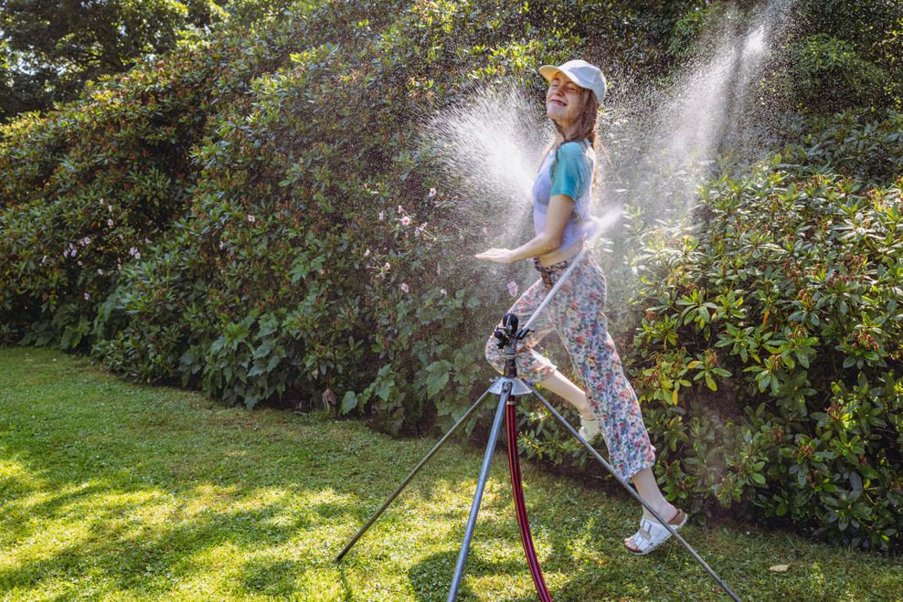 Elisa Stemsrud (13) und ihr Bruder Ewer (8) aus Norwegen kühlen sich unter einem Rasensprenger in Planten un Blomen ab.