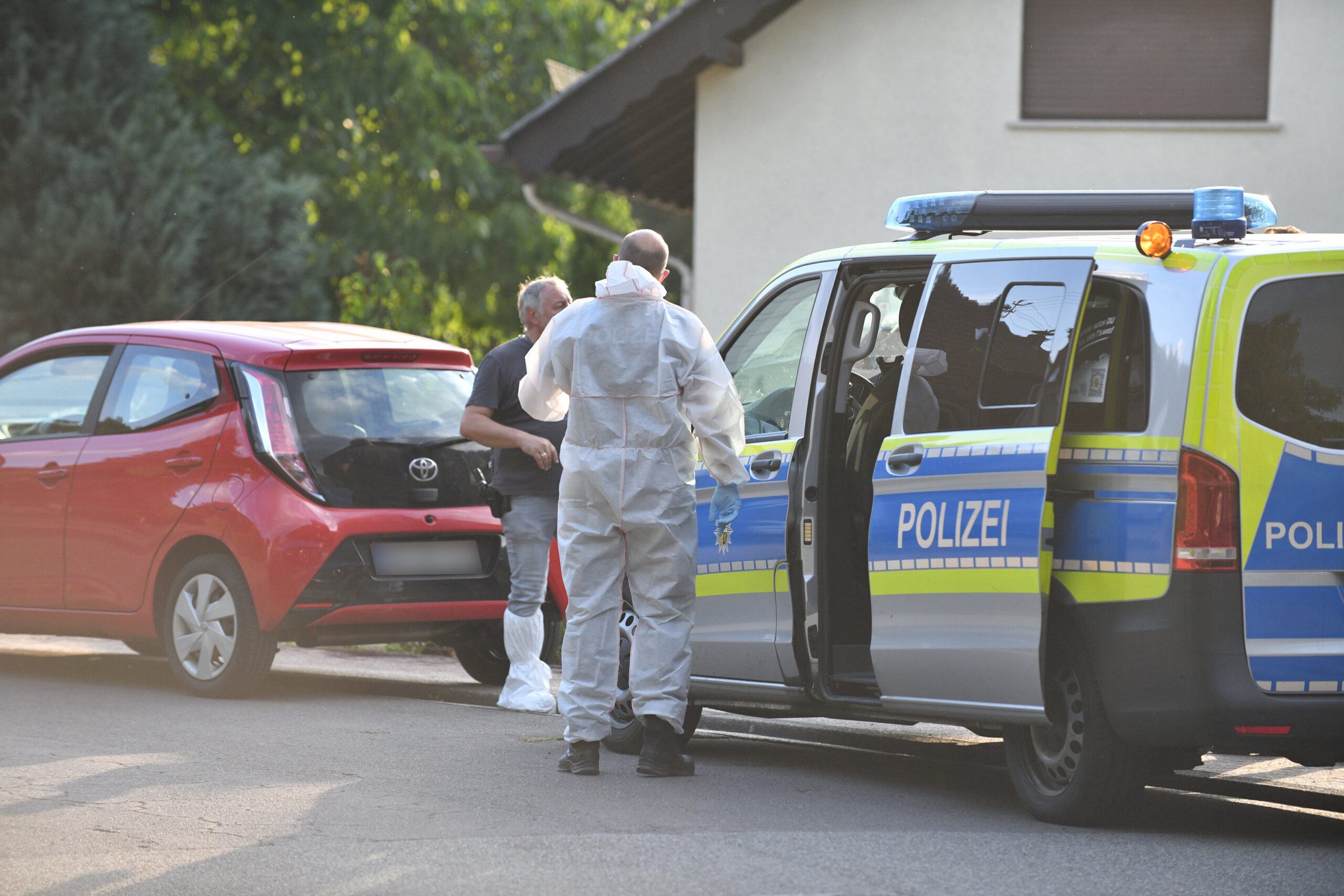 Einsatzkräfte der Polizei und Spurensicherung stehen vor einem Haus im saarländischen Ottweiler.